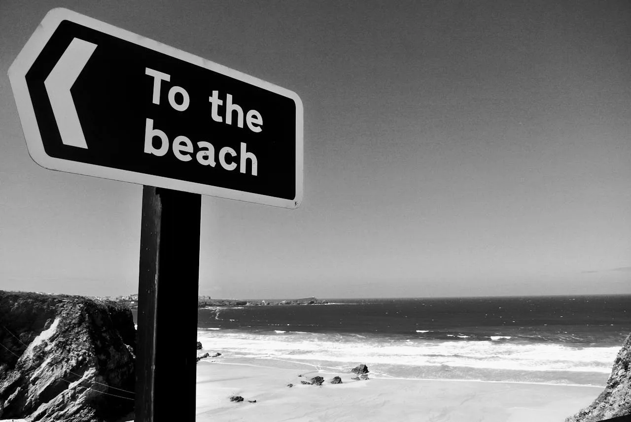 A sign pointing to the beach, with beautiful Cornish beach in background
